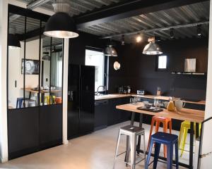 a kitchen with a wooden table and stools at Le Loft - Cocon industriel in Arques-la-Bataille