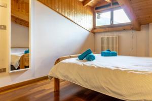 a bedroom with a bed with two blue pillows on it at Cozy Mountain View Loft, Val di Sole, Trentino in Monclassico