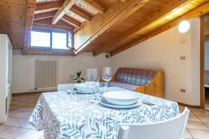 un comedor con una mesa con platos y copas de vino en Cozy Mountain View Loft, Val di Sole, Trentino, en Monclassico