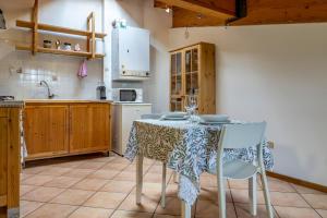 cocina con mesa con 2 sillas y cocina con electrodomésticos blancos en Cozy Mountain View Loft, Val di Sole, Trentino, en Monclassico