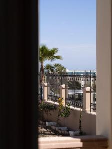 Elle offre une vue sur une clôture bordée de palmiers et l'océan. dans l'établissement Dimora NiLu', à Margherita di Savoia