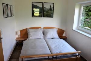 Cama en habitación con 2 almohadas y ventana en Ferienwohnung am Einödhof en Uttendorf