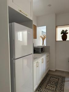 eine weiße Küche mit einem Kühlschrank und einer Mikrowelle in der Unterkunft Lishansky Since 1936 in Metulla