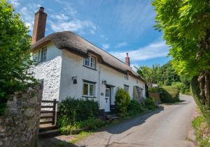 athatched cottage with a thatched roof on a road at Otters Corner in Branscombe