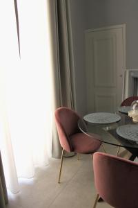 a dining room with a glass table and pink chairs at Palazzo sul Corso-Charming Appartaments in Brindisi