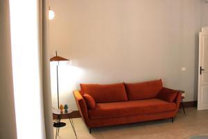 an orange couch in a living room with a lamp at Palazzo sul Corso-Charming Appartaments in Brindisi