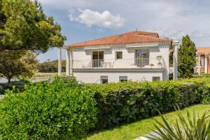a white house with a balcony and bushes at L'Hollywood Zen in Saint-Jean-de-Monts