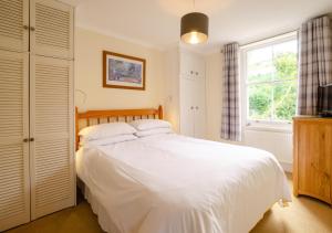 a bedroom with a white bed and a window at Causeway Cottage in Beer