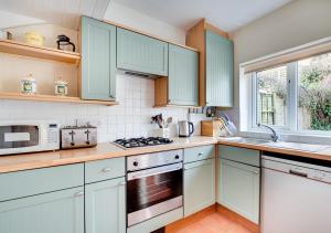 uma cozinha com armários azuis e um forno com placa de fogão em Purley em Beer