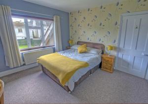 a bedroom with a bed with a yellow blanket on it at Dalmose in Seaton