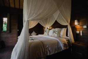 a bedroom with a large bed with a canopy at Sunset Star Huts in Nusa Lembongan