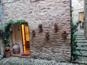 un edificio in pietra con piante in vaso accanto a una porta di Nel vicolo dei Baci - Casa vacanze al Bacio a Spello