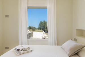 um quarto com uma cama branca e uma janela em Villa La Guaceta by Wonderful Italy em Carovigno