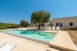 uma piscina com cadeiras e uma casa em Villa La Guaceta by Wonderful Italy em Carovigno