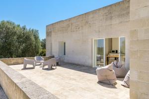 uma parede de pedra com cadeiras e mesas num pátio em Villa La Guaceta by Wonderful Italy em Carovigno