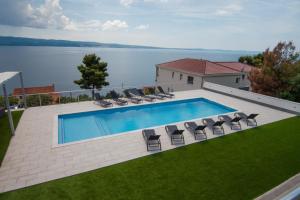 een zwembad met stoelen en uitzicht op het water bij Villa Stipe in Jesenice