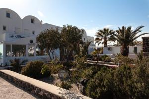a large white building with palm trees in front of it at Caldera Butterfly Villas in Fira