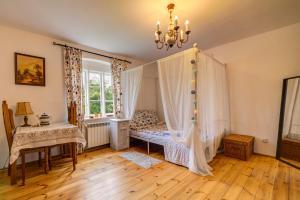 - une chambre avec un lit à baldaquin et une fenêtre dans l'établissement Uroczysko Skomackie, à Stare Juchy