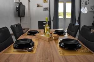 una mesa de comedor con platos negros y una botella de vino en Apartman Belisima Deluxe, en Rab