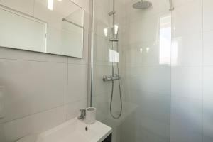 La salle de bains blanche est pourvue d'une douche et d'un lavabo. dans l'établissement Gorgeous Studio - 2 persons - Heart Cannes, à Cannes
