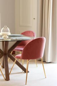 a table with two pink chairs and a glass table at Palazzo sul Corso-Charming Appartaments in Brindisi