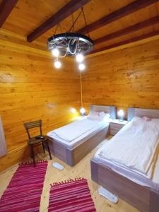 a bedroom with two beds in a wooden room at Dvokrevetne Sobe - Snežana in Ležimir
