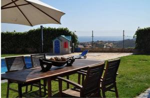 una mesa de madera con sillas, una sombrilla y una casa para perros en Villa Brisas - Preciosa villa con gran intimidad y piscina, en Segur de Calafell