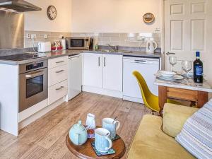 a kitchen with white cabinets and a table in a room at The Nook @ Drop Anchor in Portishead
