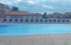 een groot blauw zwembad met stoelen en een gebouw bij Lagrange Vacances Catalana in Le Barcarès