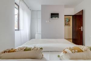 a white bedroom with two beds and a window at 3 bedrooms charming stone house in old town in Trogir