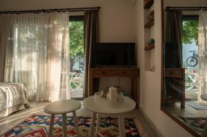 a living room with a television and a table and two stools at Sedirli Ev in Alacati