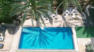 a blue swimming pool with a palm tree in front of a building at YalaRent - Liri Resort in Tiberias