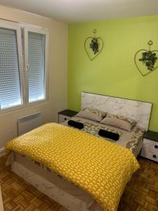 um quarto com uma cama com um edredão amarelo e 2 janelas em Best holliday Home for family newly renovated em Garges-lès-Gonesse