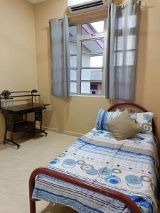 een slaapkamer met een bed, een raam en een bureau bij D' Terengganu Homestay in Kuala Terengganu