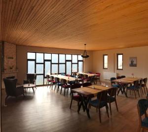 una sala da pranzo con tavoli, sedie e finestre di Şavşat Köşk Otel a Artvin