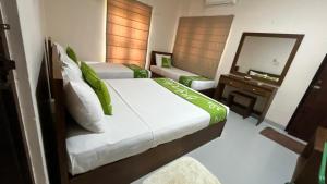 una camera d'albergo con due letti e uno specchio di Honey Tree Polonnaruwa a Polonnaruwa