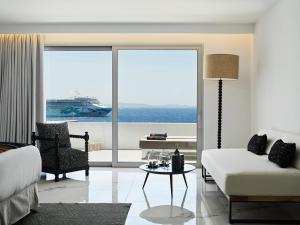 a living room with a couch and a table and a large window at Kouros Hotel & Suites in Mýkonos City