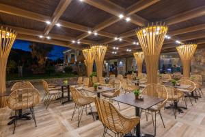 a restaurant with tables and chairs and chandeliers at Dias Hotel & Apts in Stalida