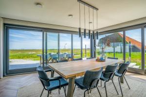 comedor con mesa y sillas y ventana grande en Natuurvilla 24 Oosterkolk, en De Waal