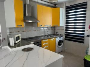 a kitchen with yellow cabinets and a washing machine at Huerto Apartment in Lucena