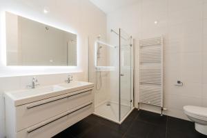 ein weißes Bad mit einem Waschbecken und einer Dusche in der Unterkunft BizStay Harbour IV in Scheveningen