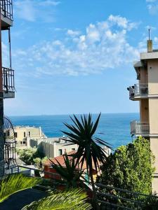 Blick auf das Meer mit Gebäuden und einer Palme in der Unterkunft Casa Mirosa in Arenzano