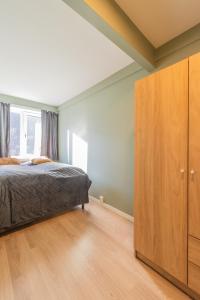1 dormitorio con 1 cama y armario de madera en Nordic Host - Dronningens Gate 12, en Oslo