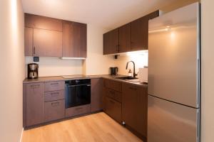 a kitchen with wooden cabinets and a stainless steel refrigerator at Nordic Host - Dronningens Gate 12 in Oslo