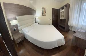 a bedroom with a white bed and a wooden floor at B & B La Pineta By La Capannina in Roccaraso