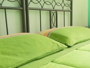two green pillows sitting on top of a bed at B&B Le Colonne in Montefusco