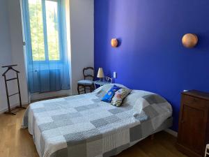 a blue bedroom with a bed with a blue wall at Gite des voyageurs in Villefort