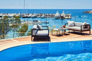 a pool with two chairs and a table next to the water at Pure Salt Port Adriano - Adults Only in Santa Ponsa