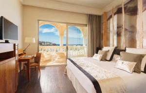 a hotel room with a bed and a desk and a window at Pure Salt Port Adriano - Adults Only in Santa Ponsa
