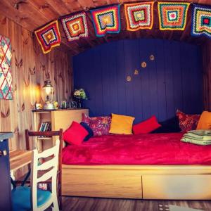 a bedroom with a large red bed with colorful pillows at Under the Oak Glamping in Caerphilly